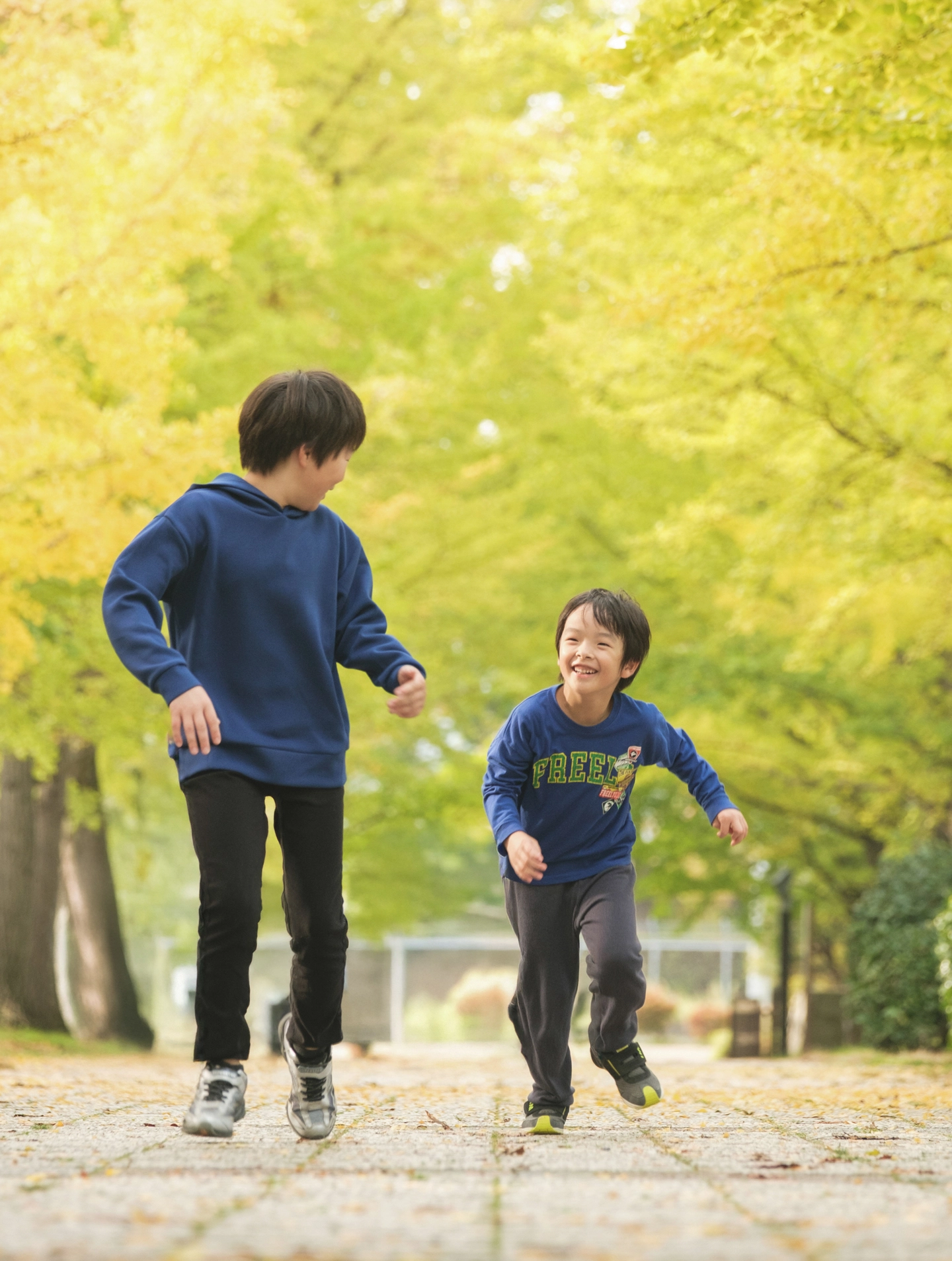 黄色い木々の下で遊ぶ親子