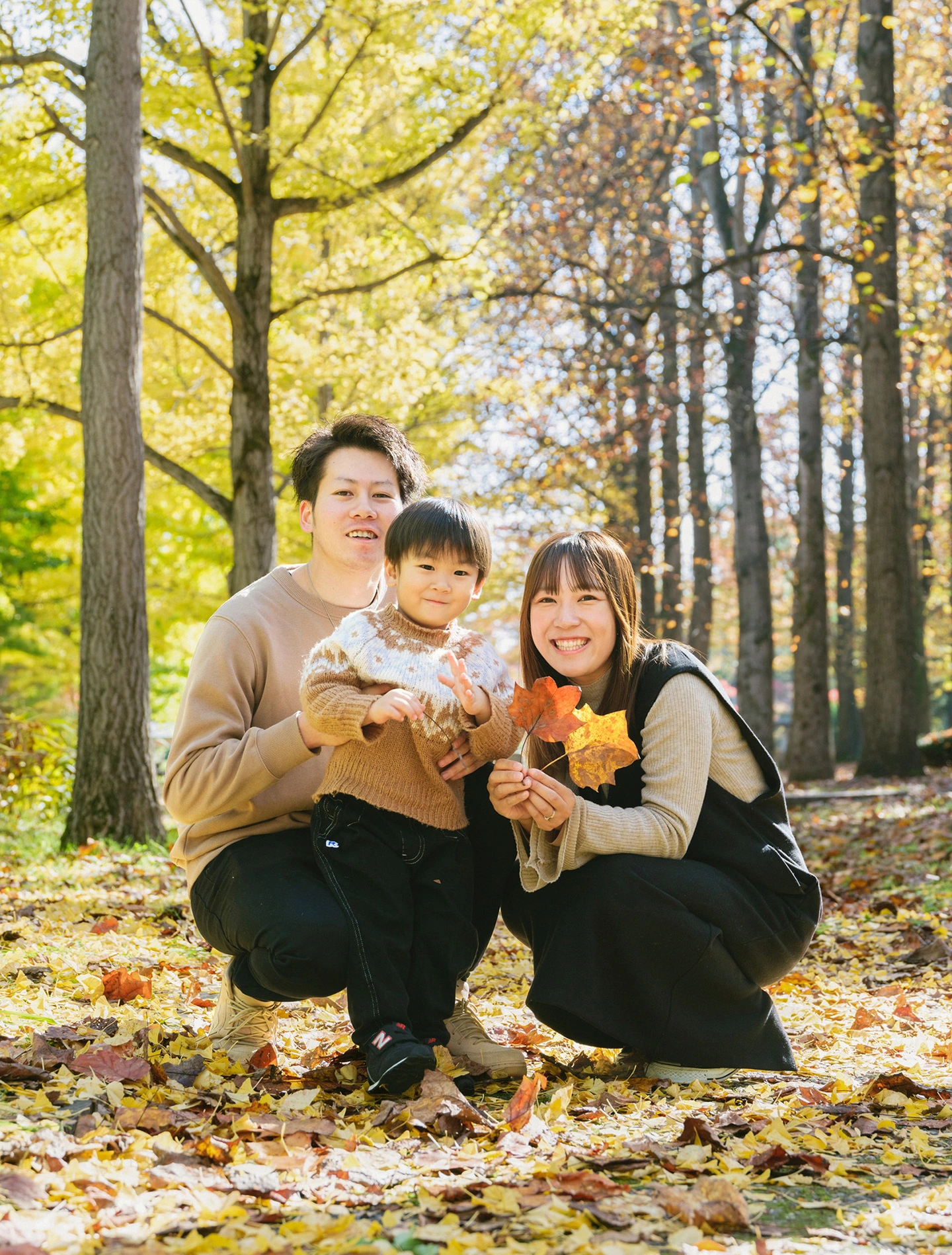 秋の木立の中で子どもを囲んで寄り添う家族