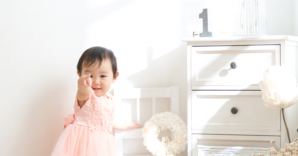 1歳の女の子がピンクのドレスで笑顔を見せるバースデー記念写真
