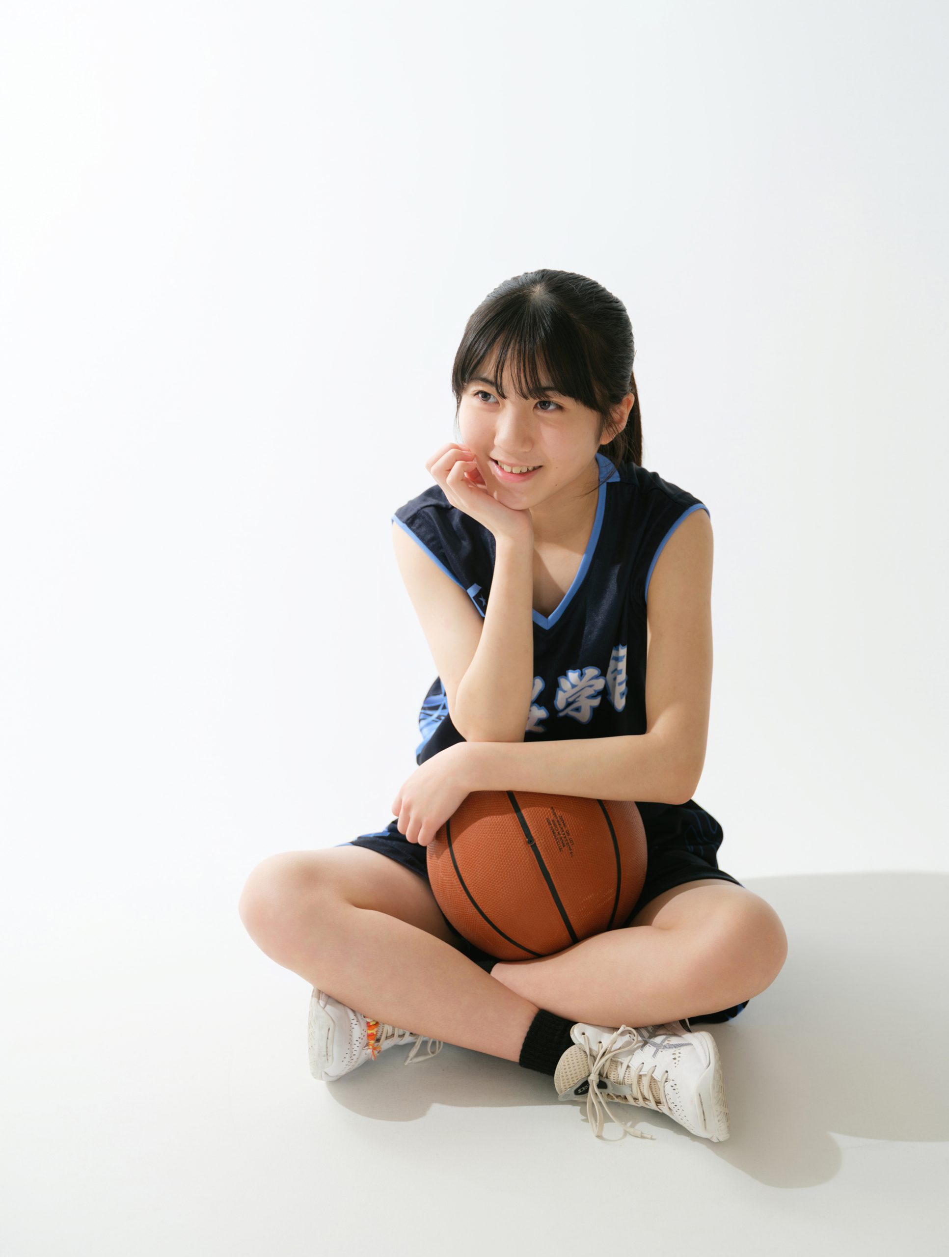 バスケットボールを抱えて笑顔を見せるユニフォーム姿