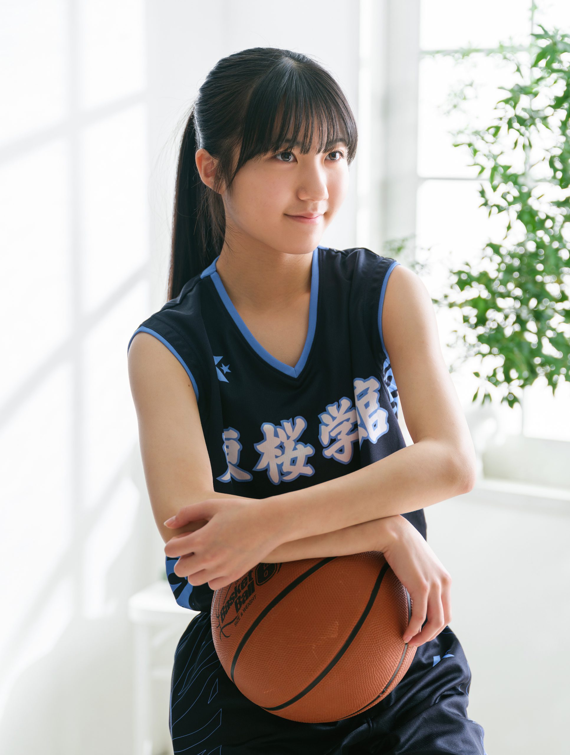 窓辺の光の中でバスケットボールを抱えるポートレート