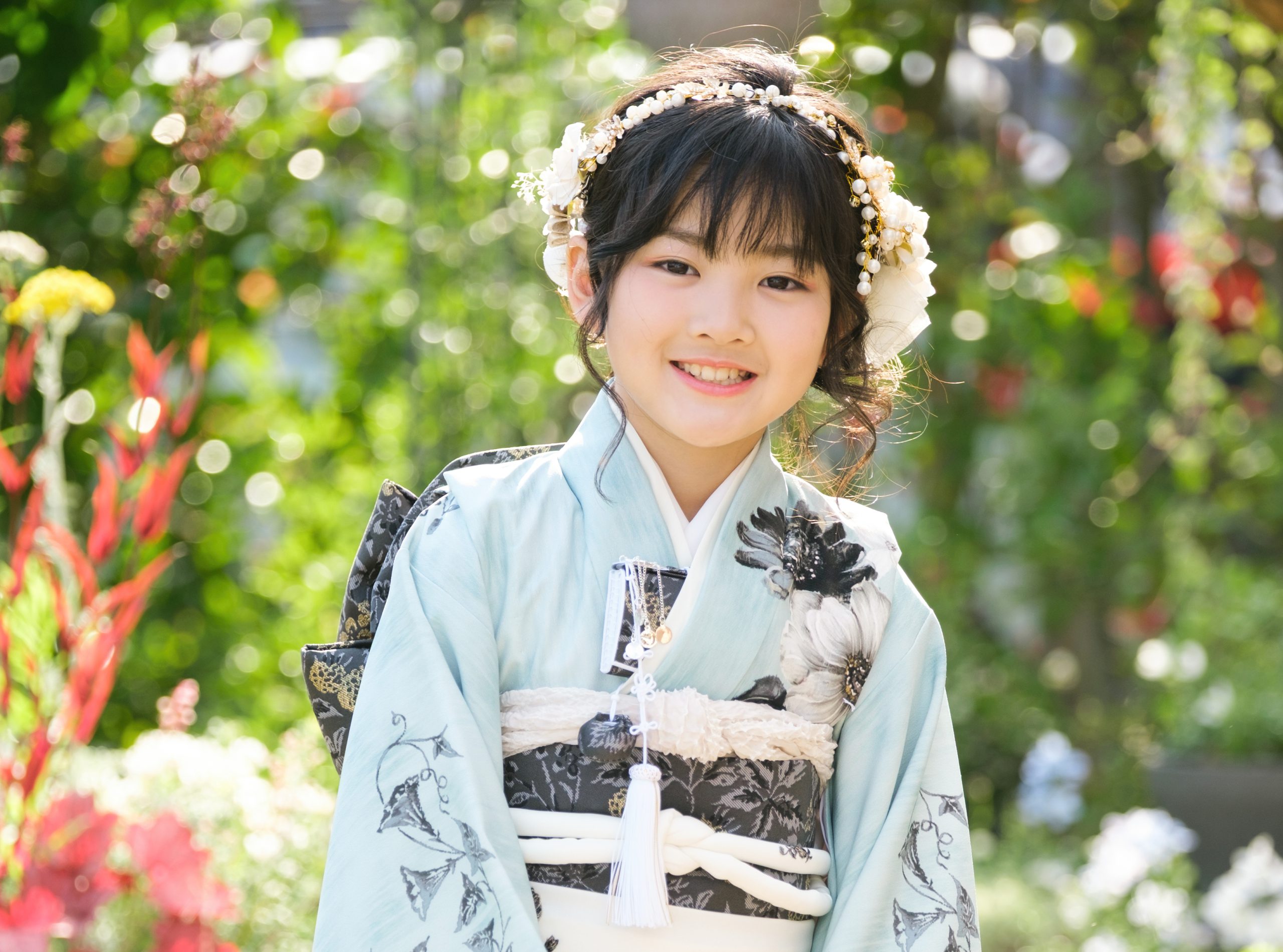 緑と花を背景にした7歳七五三の笑顔のポートレート