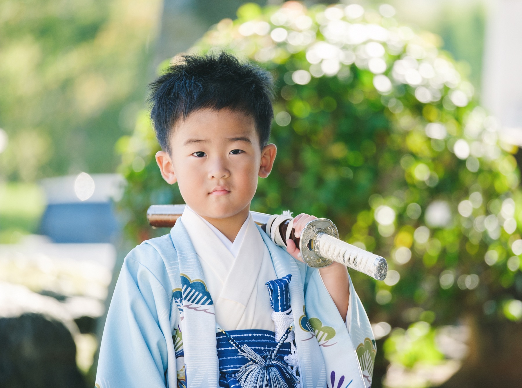 刀を肩に添え、まっすぐカメラを見つめる5歳の男の子