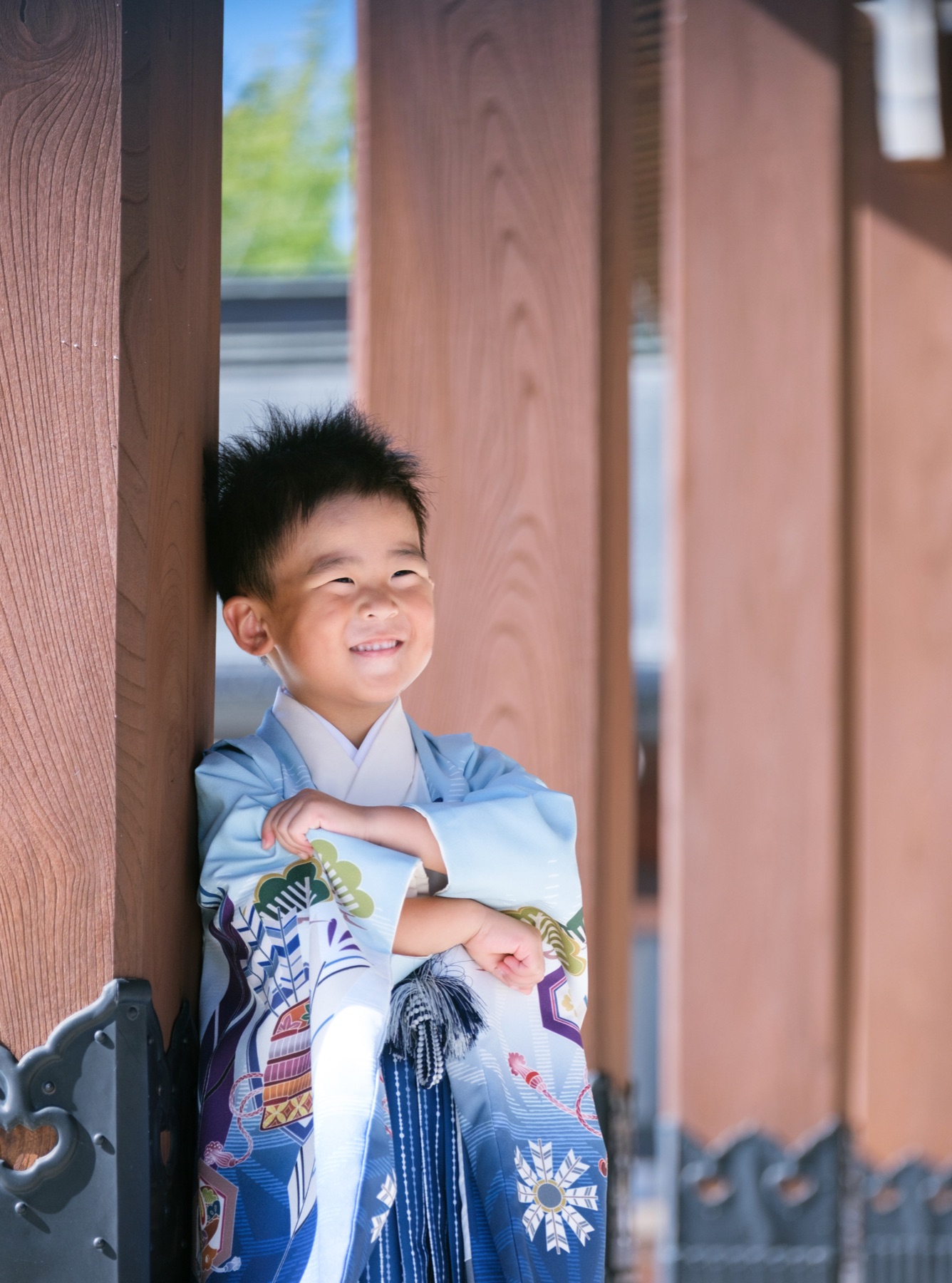 木の柱のそばで腕を組み、笑顔を見せる七五三の男の子