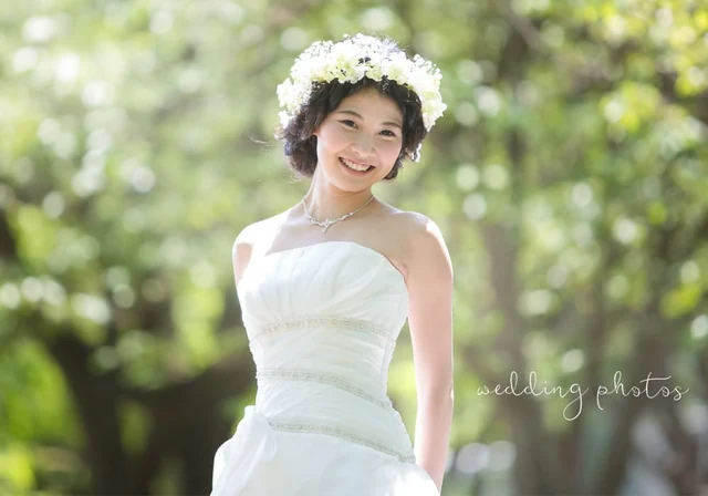 緑の中で白いドレスと花冠を身に着けた花嫁